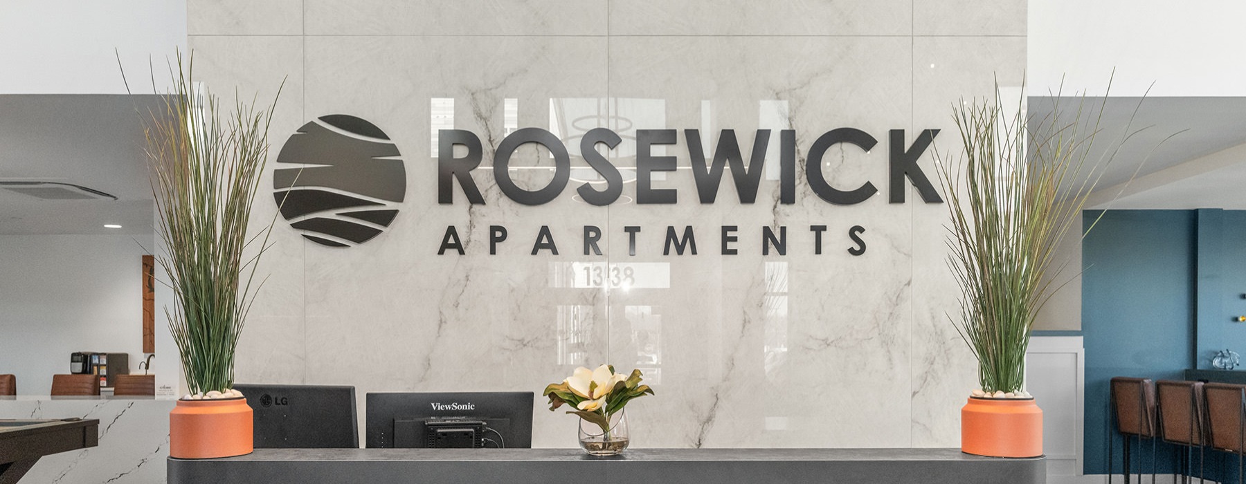 a reception desk with plants and a sign